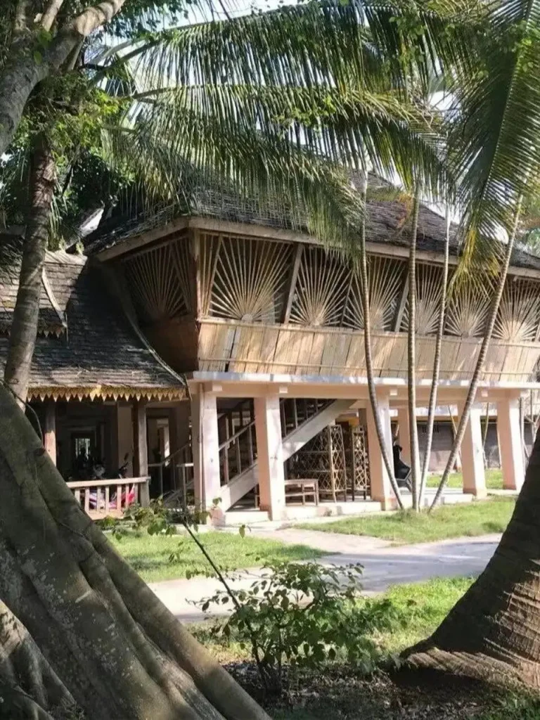Traditional Dai stilted bamboo house with thatched roof in a tropical garden