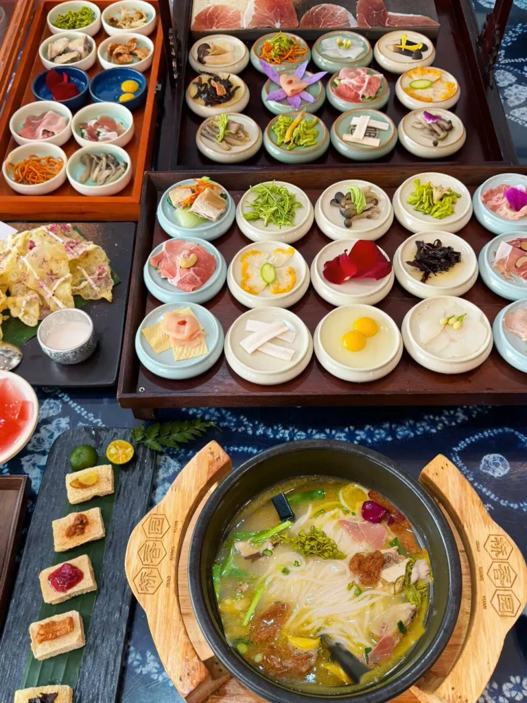 Crossing the Bridge Rice Noodles with a dozen ingredient plates surrounding a bowl of scalding chicken broth